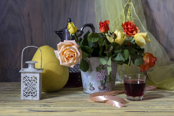 Still life. Bouquet of autumn roses on a wooden table and a glass with homemade wine close-up. - Photo, Image