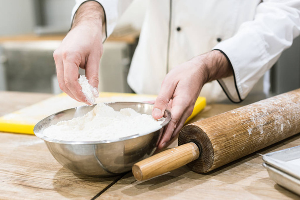 primer plano de panadero sosteniendo tazón de harina en el mostrador de madera
 - Foto, Imagen