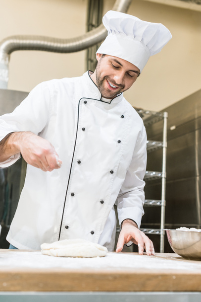 baker in white chefs uniform smiling and cooking dough in professional kitchen - 写真・画像