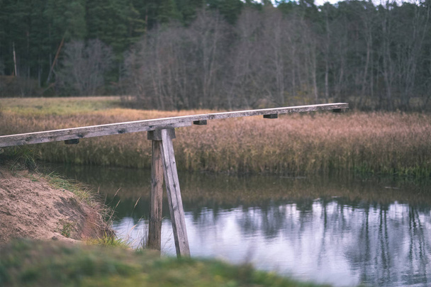 деревянный мост через воду в лесу осенью с серыми цветами - старинная пленка выглядит
 - Фото, изображение