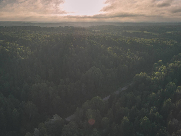 Drohnenbild. Luftaufnahme des ländlichen Raums mit Feldern und Wäldern und Wasserspiegelungen im Fluss an bewölkten Frühlingstagen. Lettland - alter Film-Look - Foto, Bild