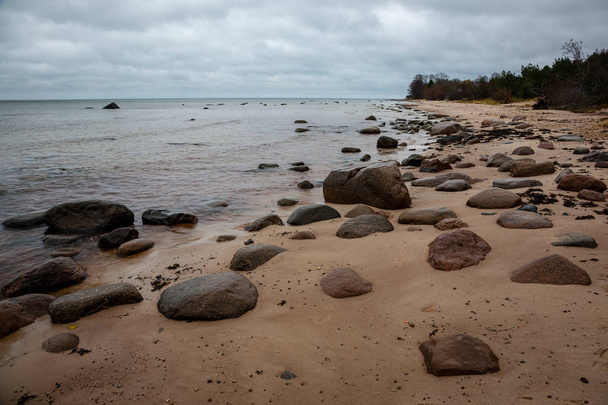 skalnaté pobřeží v Lotyšsku toku vody v moři velké kameny v pozdním podzimu - Fotografie, Obrázek