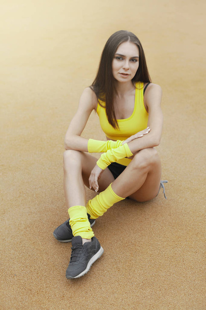 Молодая сексуальная девушка в желтом спортивном костюме на тренировочной площадке. Стиль жизни, деятельность, фитнес и спорт
 - Фото, изображение