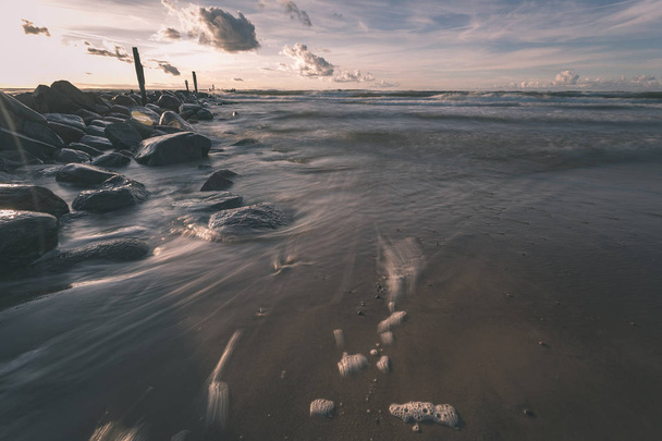 playa de mar de larga exposición con rocas y las olas lavadas de agua. imagen abstracta texturizada - aspecto de película antigua vintage
 - Foto, Imagen
