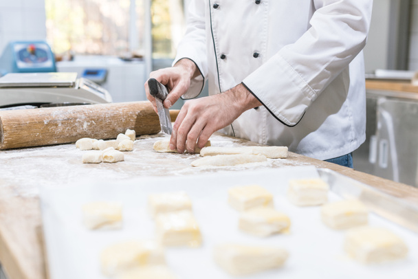 Cropped view of baker hands cutting dough on table - Fotografie, Obrázek