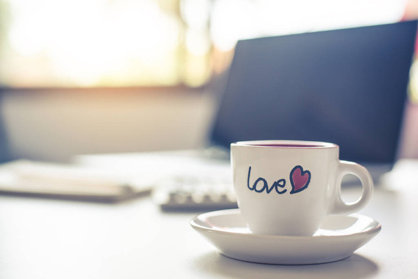Kaffeetasse mit "Liebe" steht auf dem Schreibtisch. - Foto, Bild