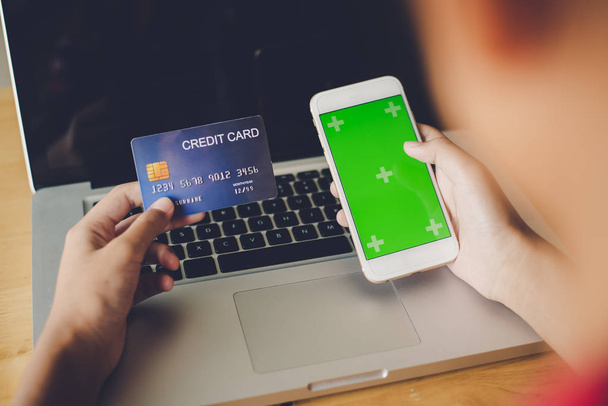 Käsi kädessään luottokortti käsissään ja löytää tietoa tuotteesta käyttäen mobiililaitteella tehdä ostoksia verkossa ja suorittaa rahoitustransaktioita. - Valokuva, kuva