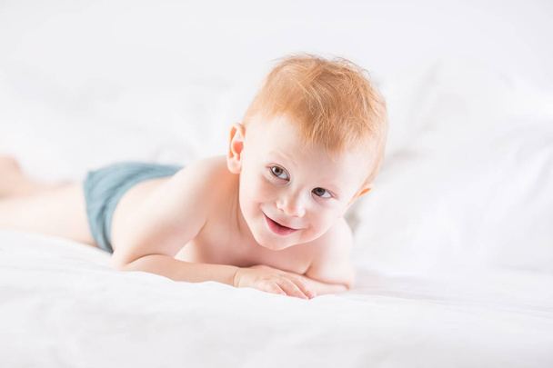 Habby young smilling child boy in white bed. - Fotó, kép