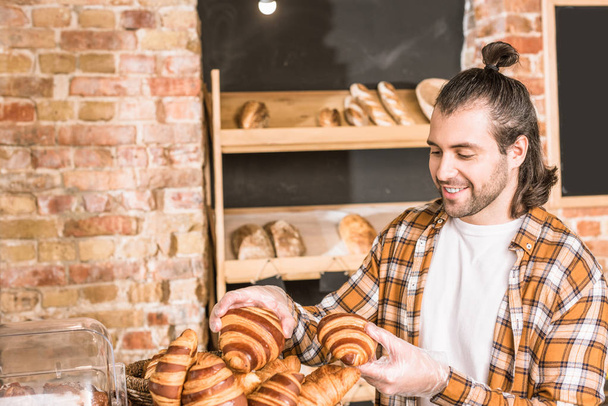Handsome seller holding pastry in bakehouse - Photo, image
