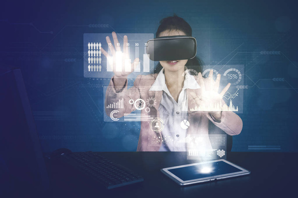 Business woman working with virtual reality glasses while touching financial graph on virtual screen - Fotografie, Obrázek