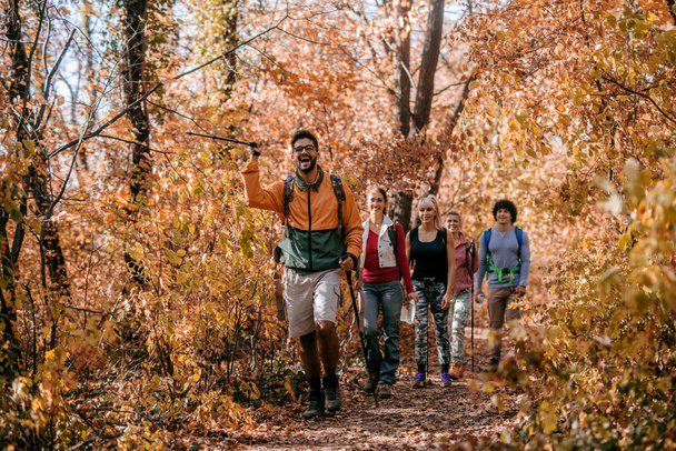 Mann zeigt anderen Wanderern beim Waldspaziergang den richtigen Weg. Herbstzeit. Erlebniskonzept. - Foto, Bild