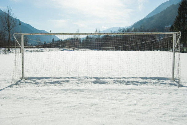 全体のサッカー ゴール ネットと雪に覆われたフィールドと山のパノラマ - 写真・画像