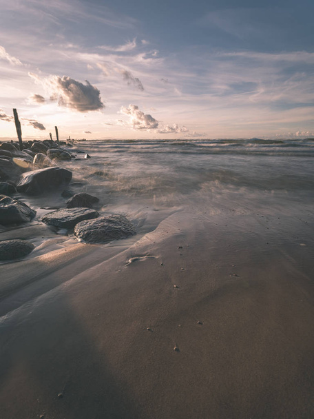 playa de mar de larga exposición con rocas y las olas lavadas de agua. imagen abstracta texturizada - aspecto de película antigua vintage
 - Foto, Imagen