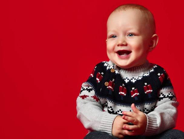 Funny little baby wearing warm knitted Christmas sweater at studio on cold winter day. - Foto, imagen