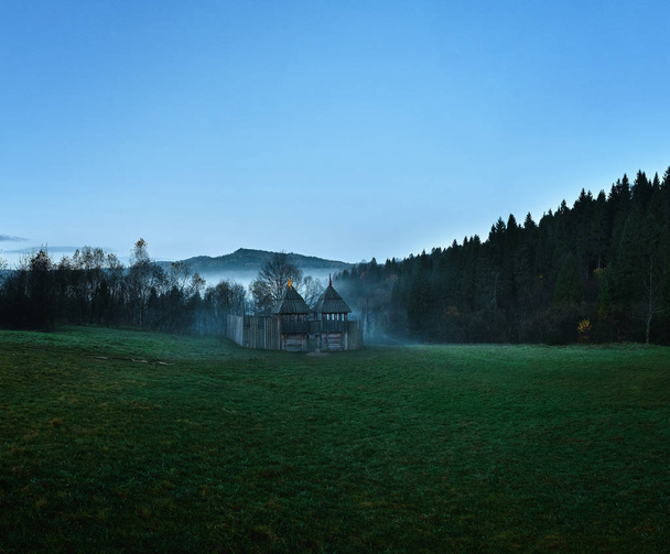ancient wooden fortress, fortification in a clearing in the forest at dawn on a foggy morning - Fotó, kép