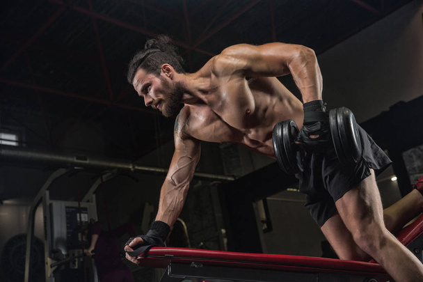 Muscular athletic bodybuilder fitness model posing after exercises in gym - Foto, Bild