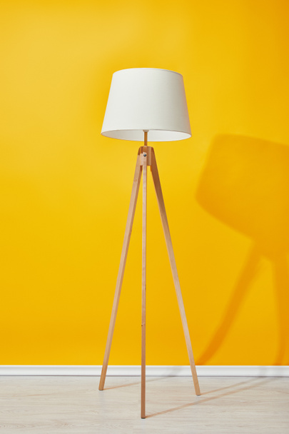 Minimalista padló lámpa közelében világos sárga fal - Fotó, kép