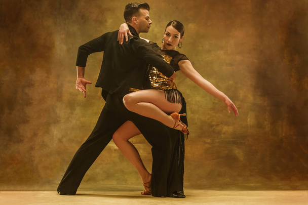 Dance ballroom couple in gold dress dancing on studio background. - Foto, imagen