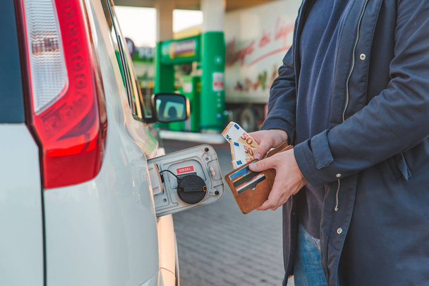muž si eura z peněženky a dát do nádrže auta. zdražení benzinu. čerpací stanice koncept - Fotografie, Obrázek
