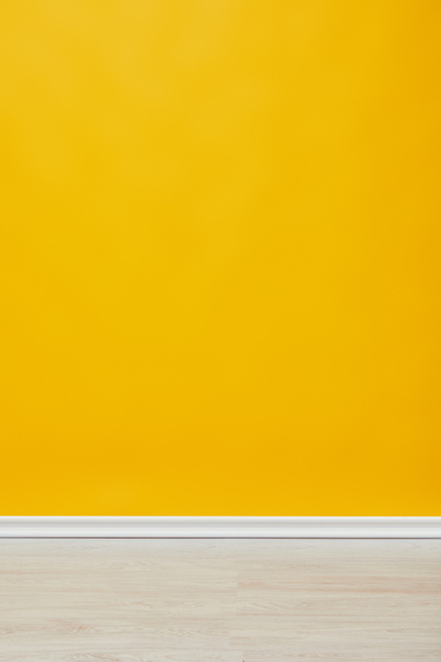 bright empty yellow wall with wooden floor  - 写真・画像