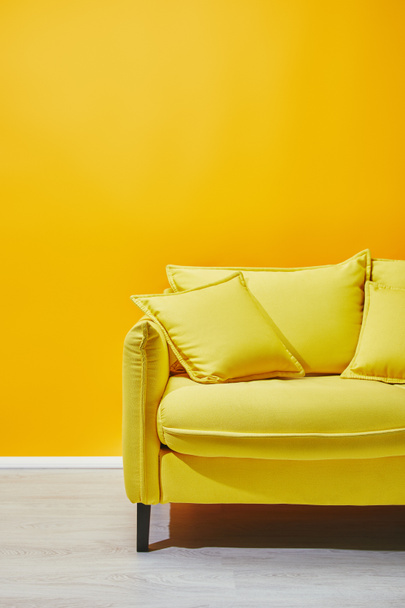 Sofa with pillows near bright yellow wall - Foto, imagen