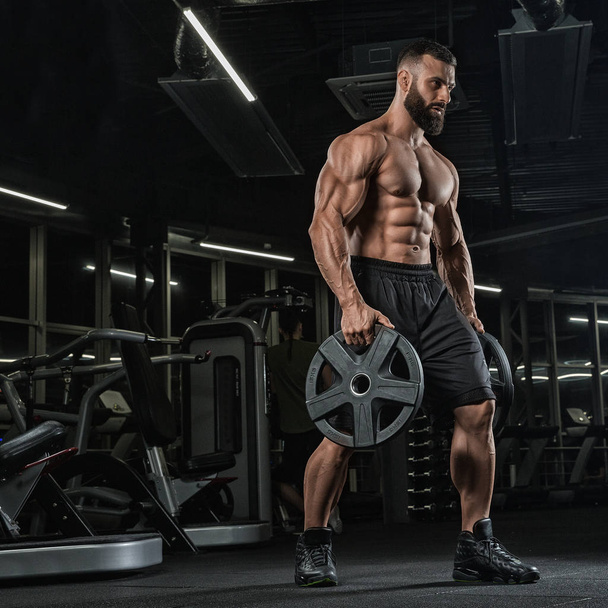 Atraente fisiculturista muscular alto fazendo pesados deadlifts no centro de fitness moder. - Foto, Imagem