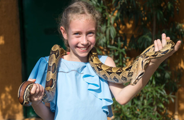 Милая маленькая девочка держит змею в руках
. - Фото, изображение
