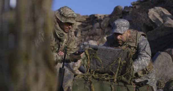 Aseistetut sotilaat katsovat tietokonetta.
 - Materiaali, video