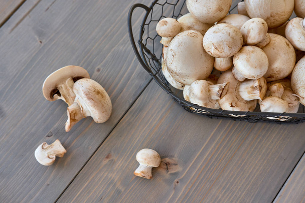 Cogumelos de champignon em uma cesta em um fundo de madeira
 - Foto, Imagem