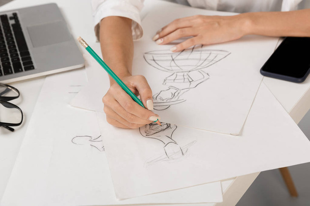 Cropped photo of young business woman designer isolated over grey wall background sitting at the table drawing. - Foto, Bild
