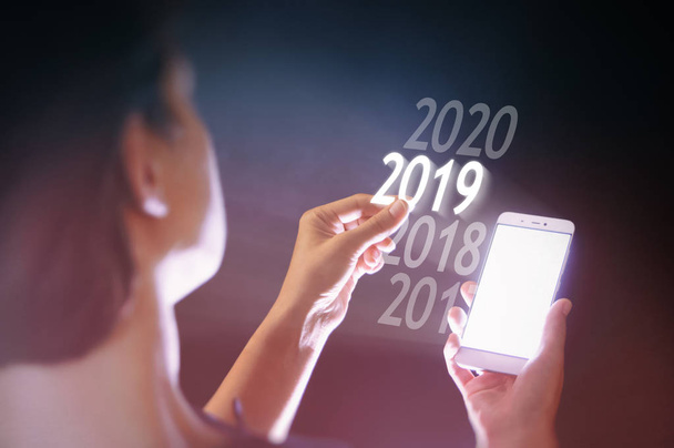 Жінка обирає 2019 рік на своєму смартфоні. Новий 2019 рік у високих технологіях
. - Фото, зображення