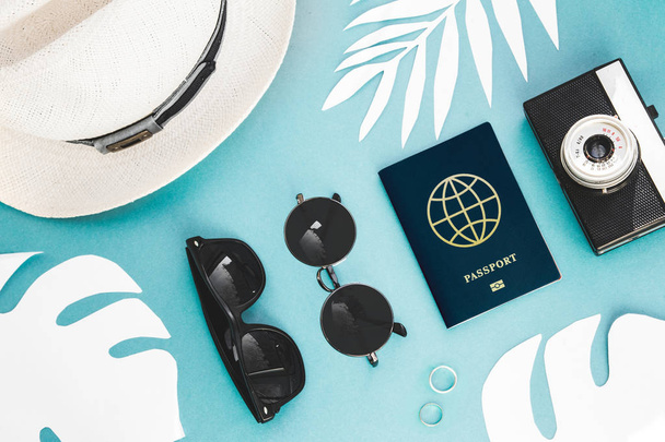 Flatlay путешественников аксессуары на синем фоне с пальмовым листом, фотоаппарат, международный паспорт и солнцезащитные очки. Концепция путешествия или отпуска с видом сверху. Летний фон
. - Фото, изображение