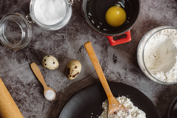 Ingredients and utensils for baking. Spoon with flour, dishes, eggs,  butter salt and rolling pin on a grey background. Flat lay.  - Foto, immagini
