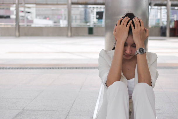 Frustré stressé jeune femme d'affaires asiatique avec les mains sur le visage assis à l'extérieur. - Photo, image