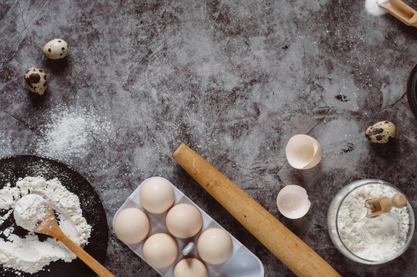 Ingredients and utensils for baking. Spoon with flour, dishes, eggs,  butter salt and rolling pin on a grey background. Flat lay. Text space - Foto, Bild