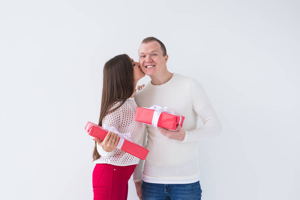 People, christmas, birthday, holidays and valentines day concept - happy young man and woman with gift boxes on white background with copy space. - Foto, Imagen