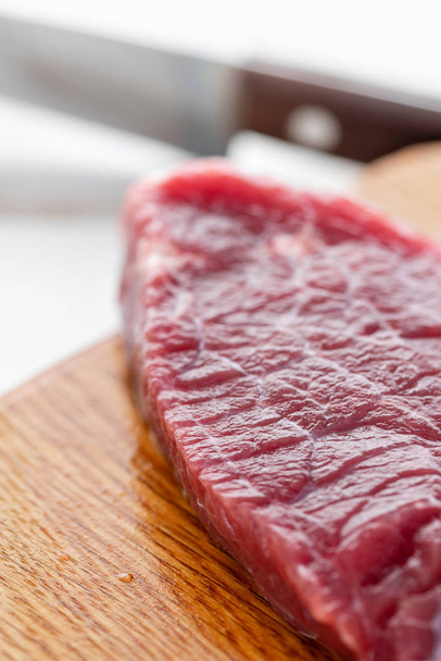 Morning in the kitchen. Raw meat. Raw fresh beef steak on a wood cutting board. White wooden background, top view, copy space, Daylight - Foto, Imagem
