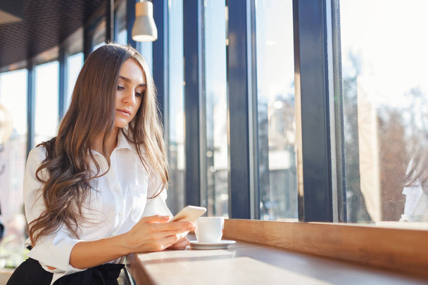 Jeune belle femme en vêtements de travail utiliser smartphone dans un café
 - Photo, image