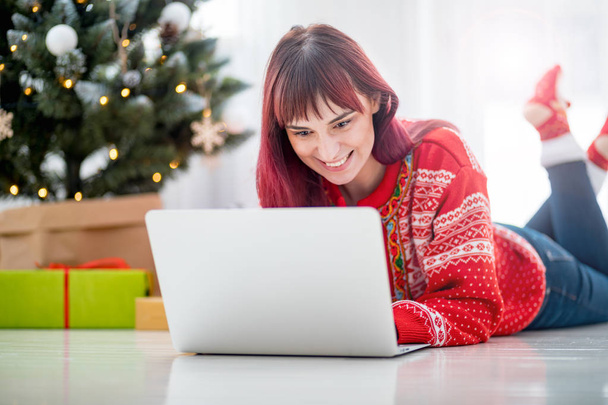 Young woman using laptop next to xmas tree, Christmas shopping online - Foto, Imagem