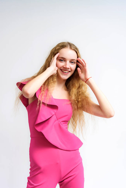 Studio portrait of a beautiful girl blonde teenager on a white background in various poses. She is standing with different emotions right in front of the camera, smiling and looking happy. - Valokuva, kuva