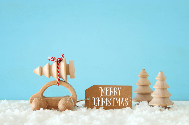 Wooden car carrying a christmas tree in front of pastel background - Foto, Imagem