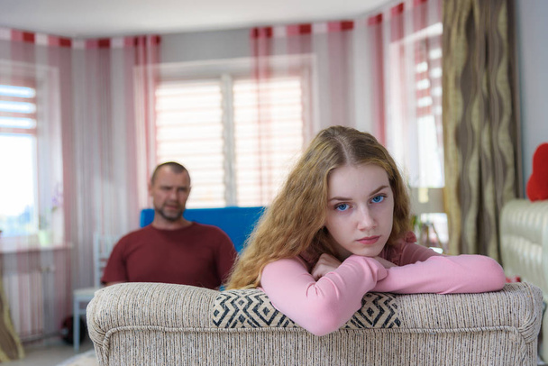 Family problems, family relations father and teen daughter in a room on the sofa. They are sitting right in front of the camera, arguing and looking displeased. - Fotografie, Obrázek