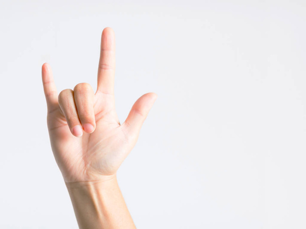 Hand signs showing thumb, forefinger and little finger raised up and middle finger and ring finger down, that meaning I love you on white background with copy space. - Photo, Image