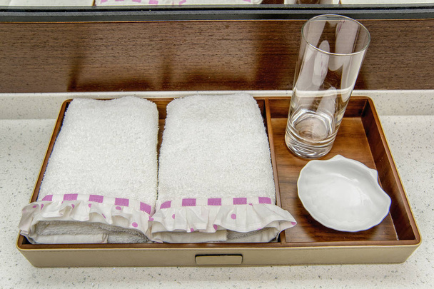 weiße Frottee-Handtücher mit rosa Schleife. Weiche sanfte Handtücher für das Badezimmer. Creme Handtuch Set für die Familie. Handtuch mit Rüschen mit weißem und rosa Muster. Handtücher liegen auf dem Tisch. - Foto, Bild