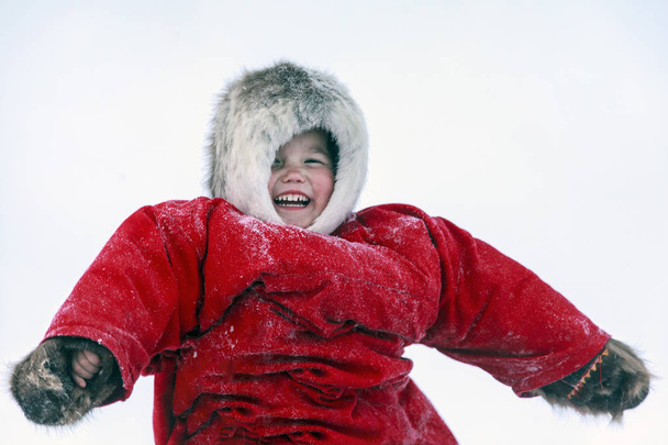 A resident of the tundra, indigenous residents of the Far North, tundra, open area, children ride on sledges, children  in national clothes,Little girl in red clothes - Фото, изображение