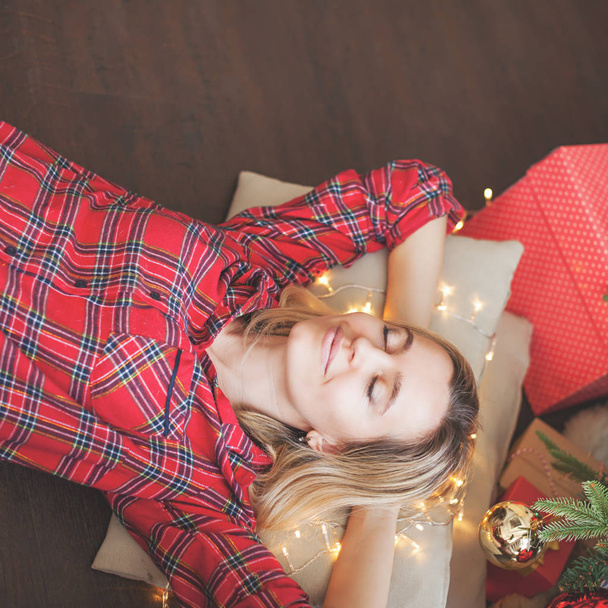 Woman lies and dreams under Christmas tree - Fotoğraf, Görsel