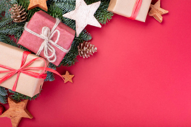 Χριστουγεννιάτικη σύνθεση. Διακοσμήσεις Χριστουγέννων κόκκινο, κλαδιά δέντρων ελάτης με παιχνίδια δώρο κουτιά σε κόκκινο φόντο. Επίπεδη lay, top view, αντίγραφο χώρου - Φωτογραφία, εικόνα
