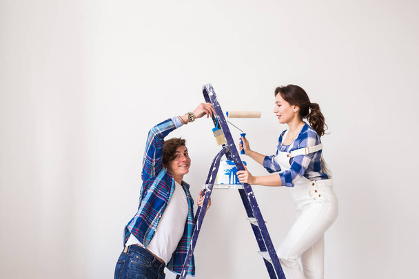 Familie, renovatie, geluk en herinrichting concept - jonge gezin reparatie doen, samen met het schilderen van muren en lachen - Foto, afbeelding