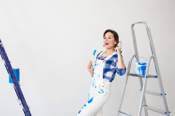 Gente, renovación y concepto de trabajo - Hermosa mujer de pie con escalera y paredes de pintura
 - Foto, imagen