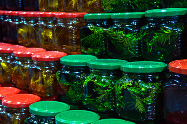 Banks with different kinds of honey in the market. Honey with fir and Linden leaves in cans. - Φωτογραφία, εικόνα
